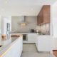 Grip ledge lighting in White kitchen with grey countertop and wood wall cabinets in Dubai by Goettling Interiors.